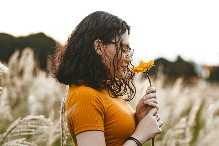 Woman sniffing flower for aromatherapy 101 