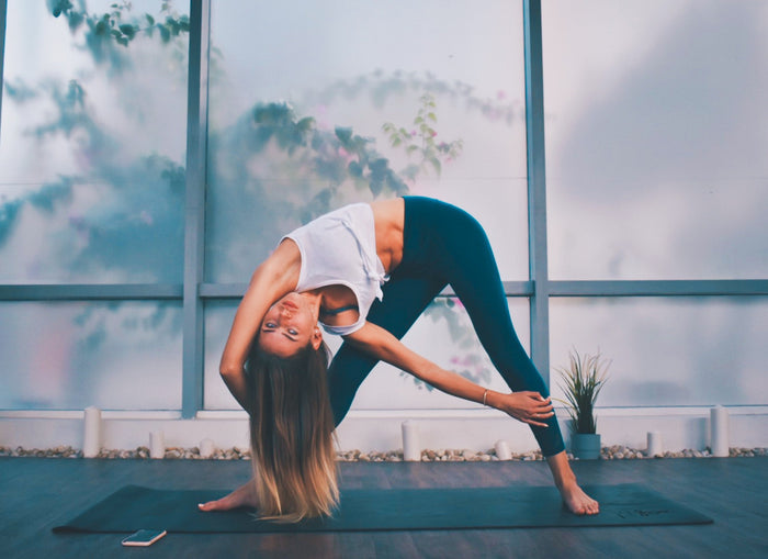 Woman stretching glutes on yoga mat 