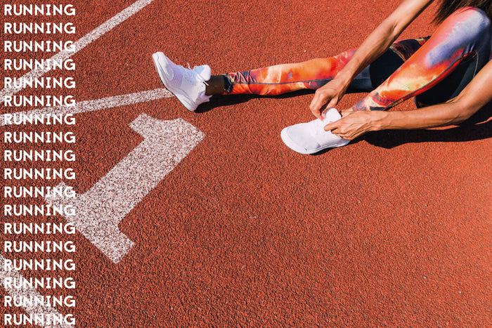 Woman tying running shoes on race track  